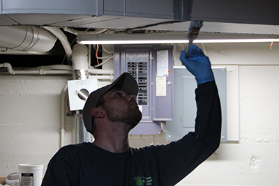 Image shows a worker sealing the duct system in a house to maximize energy savings.