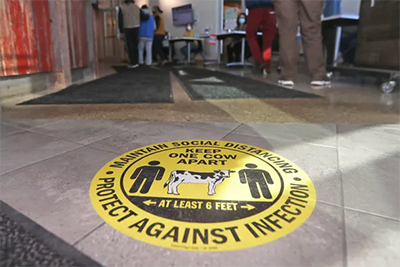 Image shows a closeup of a COVID-19 social distancing marker on the floor.